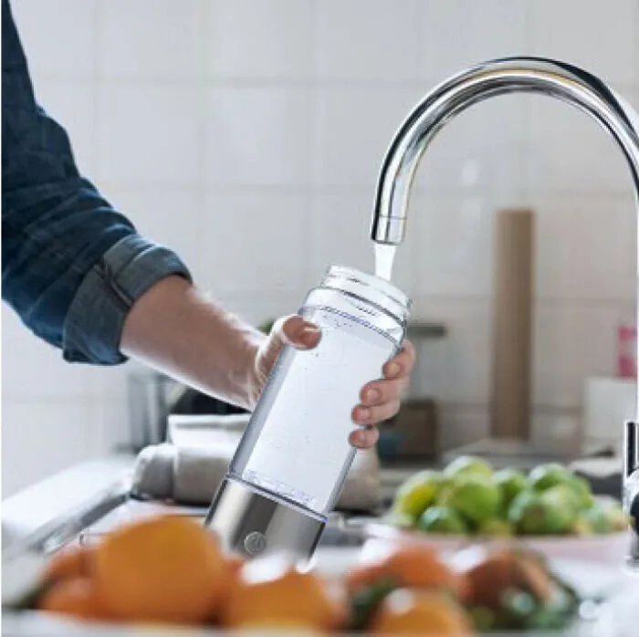 Filling the glass bottle with water from a kitchen tap
